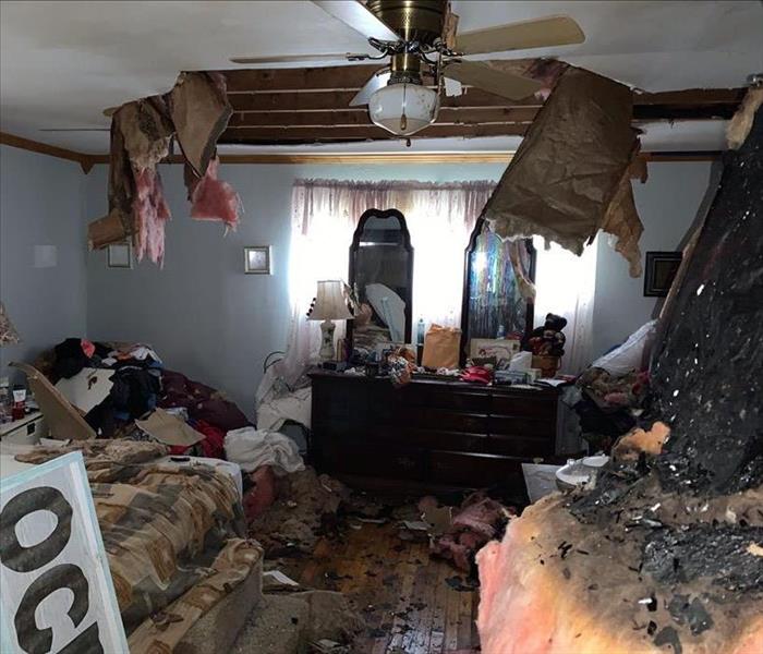 A bedroom after a fire with insulation falling and fire damage
