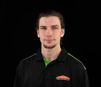 Man wearing a black SERVPRO shirt with brown hair and smiling.