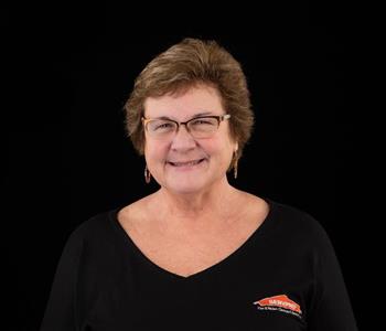 Women wearing black SERVPRO shirt with brown hair, glasses and smiling.